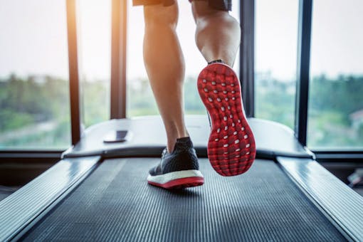 Male feet in sneakers running on the treadmill at the gym.